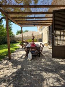 eine Terrasse mit einem Tisch und Stühlen unter einer hölzernen Pergola in der Unterkunft Villa Maros in Scicli