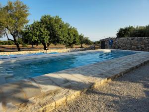 einen Pool mit einer Steinmauer und Bäumen in der Unterkunft Villa Maros in Scicli