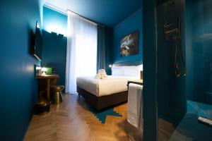 a bedroom with blue walls and a bed and a window at Fontana 16 Rooms in Milan