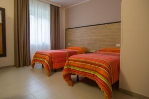 Habitación de hotel con 2 camas con sábanas de color naranja en Hotel San Marco, en Rionero in Vulture