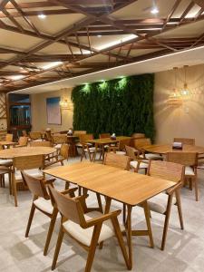 un ristorante con tavoli e sedie in legno e una parete verde di Makia Beach Experience By All a Porto De Galinhas