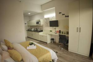 a white room with a bed and a kitchen at Luxury Apartment Near Pari Chowk in Greater Noida
