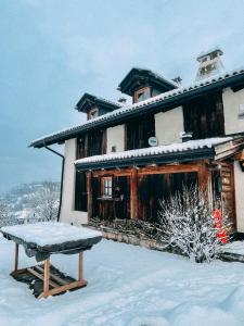 ein schneebedecktes Haus mit einer Bank davor in der Unterkunft Maso Gretel in Tesero