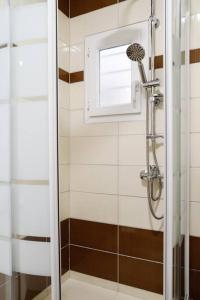a shower with a glass door in a bathroom at Cozy apartment near Airport in Koropi