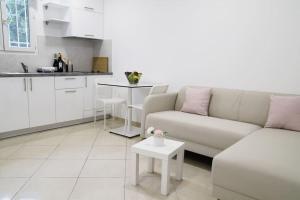 a white living room with a couch and a table at Cozy apartment near Airport in Koropi