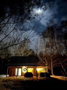 een huis verlicht in de nacht met de maan in de lucht bij Sauna House Smyczyna in Smyczyna