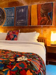 1 dormitorio con 1 cama y pinturas en la pared en Hotel "ala Residencias", en Chetumal