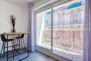 Zimmer mit einem großen Fenster mit Stühlen und einem Tisch in der Unterkunft Sainte-Catherine - Superbe appartement avec balcon Vieux-Port in Marseille