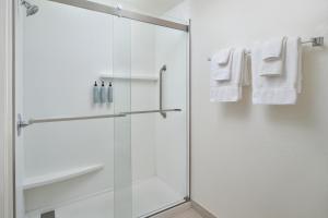 a bathroom with a shower with white towels at Courtyard Baton Rouge South in Baton Rouge