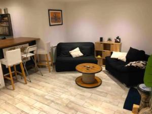 a living room with a black couch and a table at Belle maison proche du centre et des plages in Montpellier