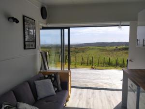 a living room with a couch and a large window at Seascape Peninsula Bach in Kaitaia