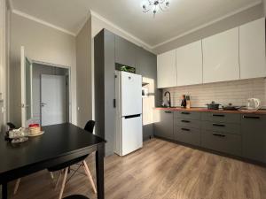a kitchen with a black table and a white refrigerator at Однокомнатные бизнес апартаменты в ЖК Заман in Atyraū