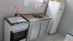 a small kitchen with a sink and a stove at Apartamento Aconchego da vovó in Peruíbe