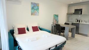ein Schlafzimmer mit einem Bett und einem Tisch sowie eine Küche in der Unterkunft Magnifique studio, piscine, Parking By Palmazur in Cannes