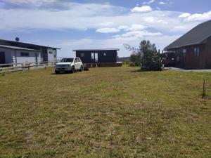 a car parked in a yard next to a house at Seascape Peninsula Bach in Kaitaia