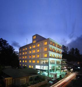 ein Gebäude, in dem nachts Licht in einer Stadt an ist in der Unterkunft Grand Plaza in Munnar