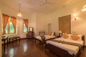 a bedroom with two beds and a desk and a piano at Udapola Bungalow in Deraniyagala