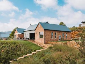 a brick house with a green roof on a hill at Star Dam Lodges in Dargle