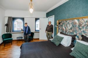 twee mannen in een hotelkamer met een bed bij Porta Superia Boutique B&B in Mechelen