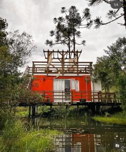 an orange house on a bridge over a body of water at Cabanas Avencal Frutas in Urubici