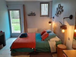 1 dormitorio con 1 cama con mantas y almohadas coloridas en Le Brame - Chambres d'Hôtes, en Avilly-Saint-Léonard