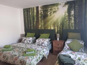 1 dormitorio con 2 camas y un mural de un bosque en Villa Feliza, en Güime