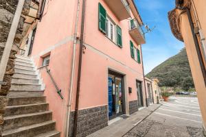 a pink building with stairs next to a street at Dal pozzo appartamento in Deiva Marina