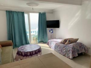 a bedroom with two beds and a couch and a window at Taghazout waves 2 in Taghazout