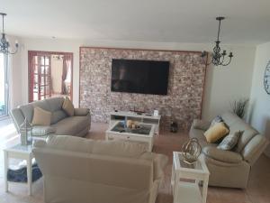 a living room with couches and a tv on a brick wall at Villa Feliza in Güime