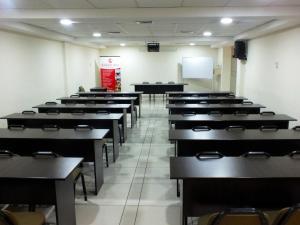 an empty classroom with desks and a white wall at Plaza Real Hotel in Encalada