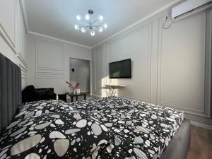 a bedroom with a black and white bed and a tv at Однокомнатные бизнес апартаменты в ЖК Заман in Atyraū
