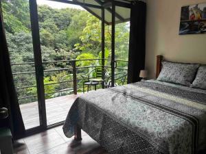 a bedroom with a bed and a balcony with a view at Casa Colibrí in Tilarán