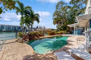 ein Pool mit zwei weißen Stühlen neben einem Haus in der Unterkunft Beach House of IRB in Clearwater Beach