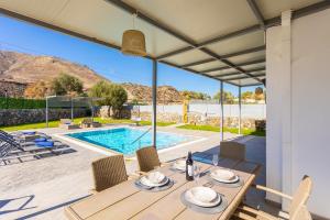a patio with a table and chairs and a swimming pool at Villa Livis 1 in Kiotari