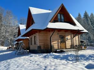 ein Haus mit Schnee auf dem Dach im Schnee in der Unterkunft Żabie Dworki Witów Luxury Chalets & SPA in Witów