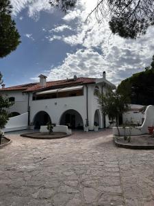 un grande edificio bianco con un ampio cortile di Villa La Caletta a Carloforte