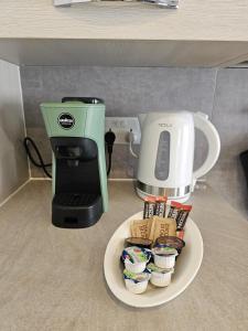 a coffee maker sitting next to a plate of cupcakes at KORZO SUITES SLIEMA III in Sliema