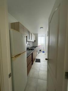 a kitchen with a white refrigerator and a hallway at Departamento La Serena por Días in La Serena