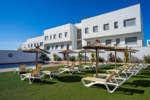 a group of chairs and umbrellas in front of a building at Hotel Andalussia in Conil de la Frontera