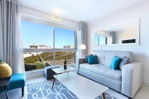 a living room with a couch and a large window at Blouberg Heights 202 by HostAgents in Bloubergstrand