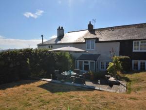 a house with a table and an umbrella in the yard at 2 Bed in Charmouth DC077 in Charmouth