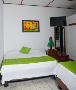 a bedroom with a white bed and a television at hospedaje oasis central in Palmira