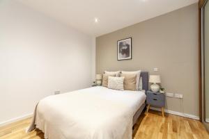 a white bedroom with a large bed and a lamp at The Camden Collection in London