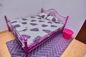 un letto rosa in una stanza con cesto di NoorVilla ad Arusha