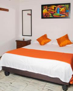 a bedroom with a large bed with an orange blanket at hospedaje oasis central in Palmira