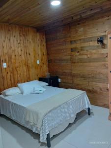 a bedroom with a bed in a wooden wall at Pousada Caminhos Do Mar in Imbituba