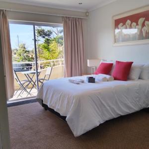 a bedroom with a large bed and a balcony at Harbour Close Home in Cape Town
