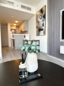 a remote control and a vase with flowers on a table at MODERN SPACIOUS STUDIO in PRIME LOCATION Central DIFC & World Trade Centre Dubai at SKY GARDENS in Dubai