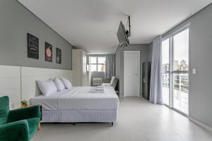 a bedroom with a white bed and a green chair at Studios novos próximos ao shopping Beira-mar #HKS in Florianópolis