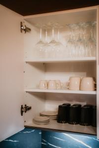 a cupboard filled with wine glasses and plates at LLR Design Apartment - Sepia Toffee im Zentrum von Koblenz in Koblenz